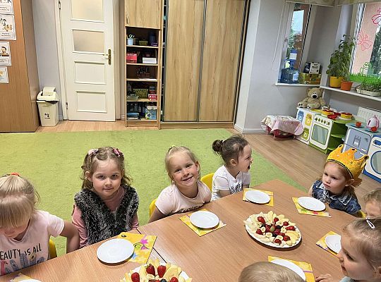 Dzieci siedzą przy urodzinowym stole