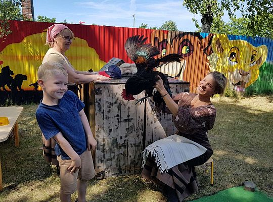 Chłopiec stoi, Pani trzyma koguta