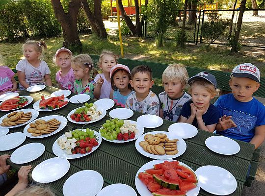 Dzieci siedzą przy urodzinowym stole