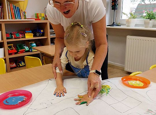 Dziewczynka odbija dłonie na papierze