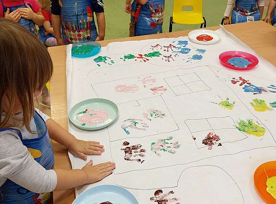 Dziewczynka odbija dłonie na papierze