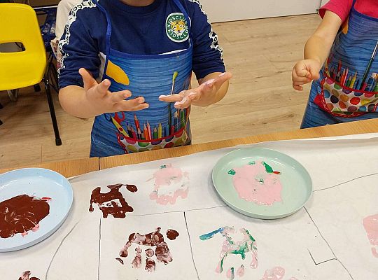 Chłopiec odbija rączki na papierze