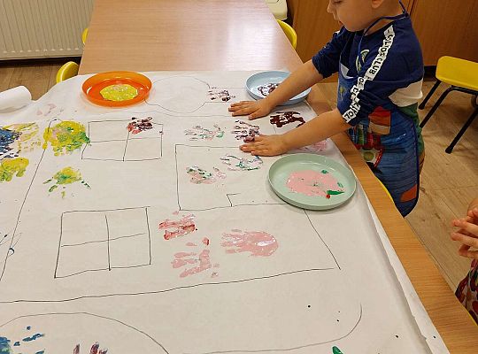 Chłopiec odbija rączki na papierze