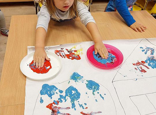 Dziewczynka odbija dłonie na papierze