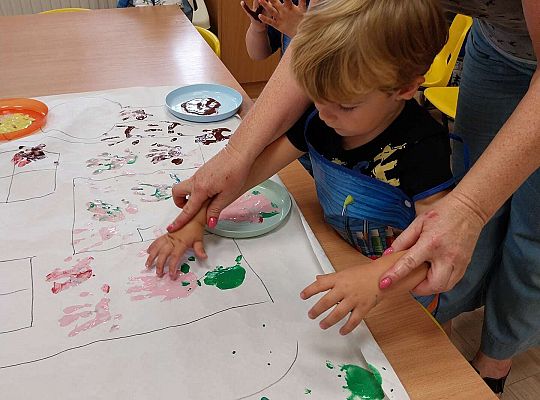 Chłopiec odbija rączki na papierze