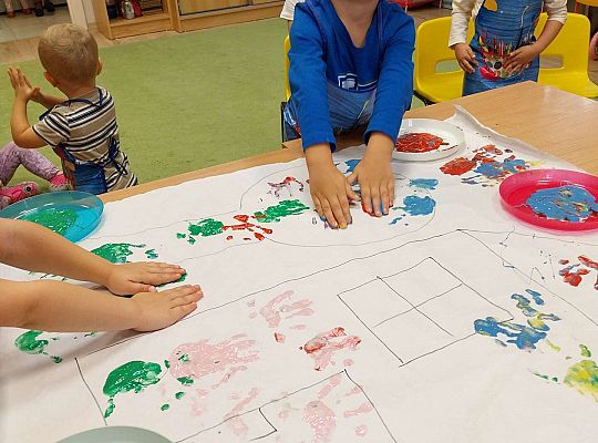 Chłopiec odbija rączki na papierze