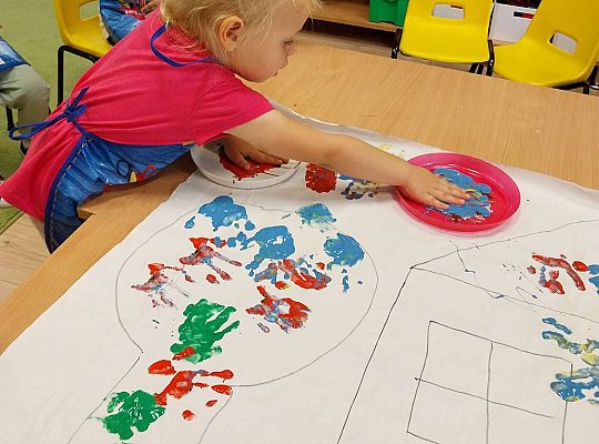 Dziewczynka odbija dłonie na papierze