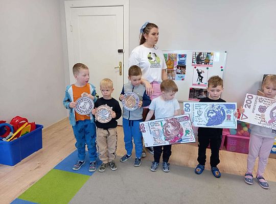 Dzieci z planszami banknotów i monet