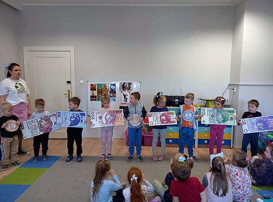 Dzieci z planszami banknotów i monet