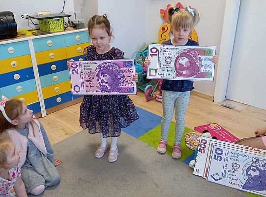 Dzieci z planszami banknotów i monet