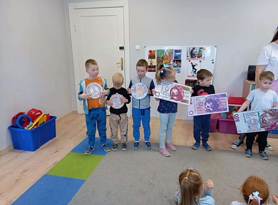 Dzieci z planszami banknotów i monet