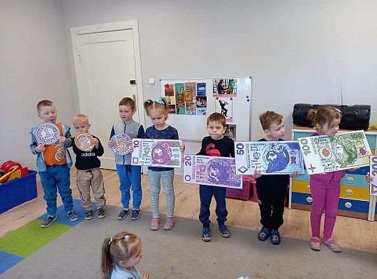 Dzieci z planszami banknotów i monet